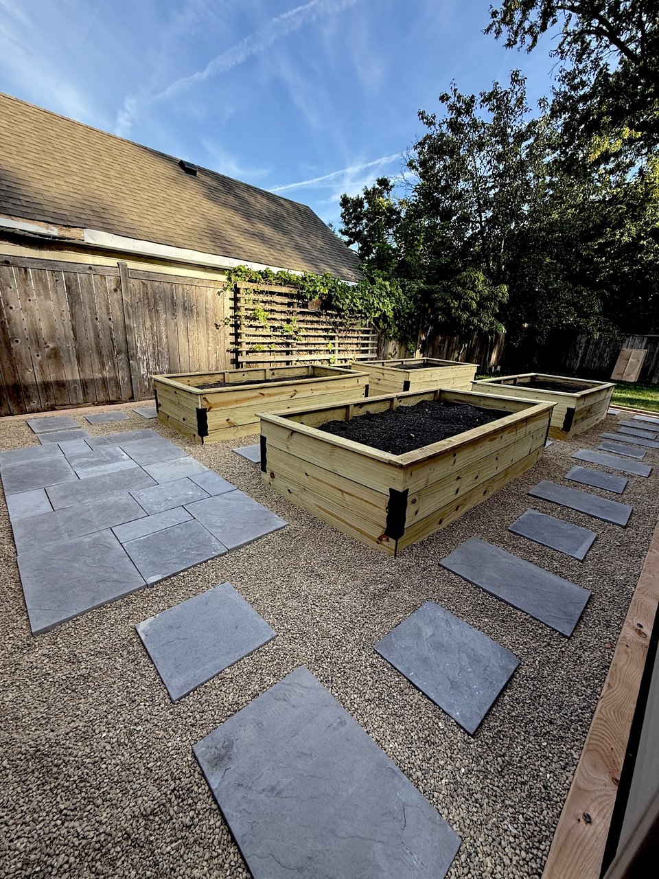 Hardscape contractors in Des Plaines: bluestone patio with stepping stones in pea gravel and four cedar raised beds on a finished install